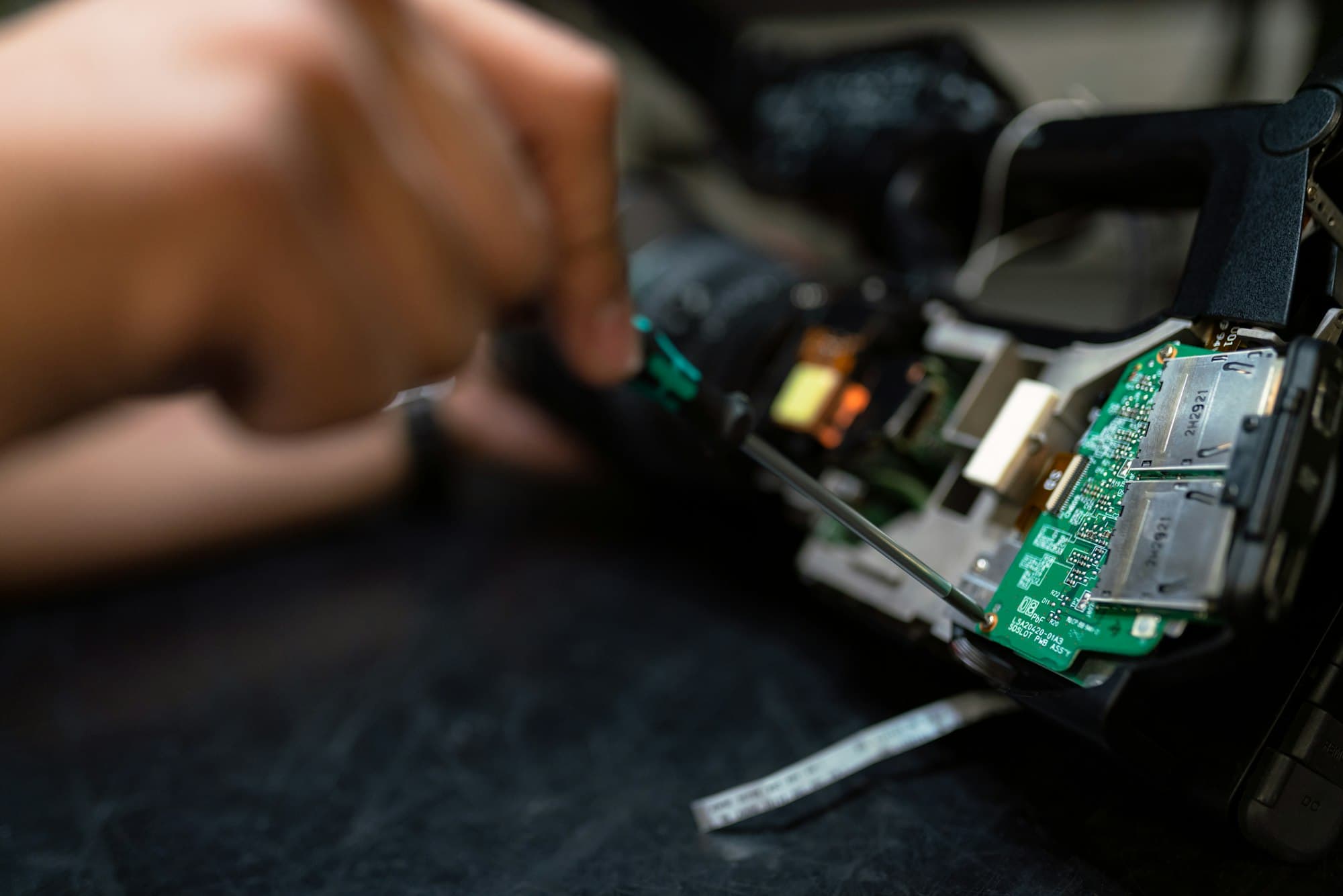 A technician's hands working on a circuit board with a precision screwdriver